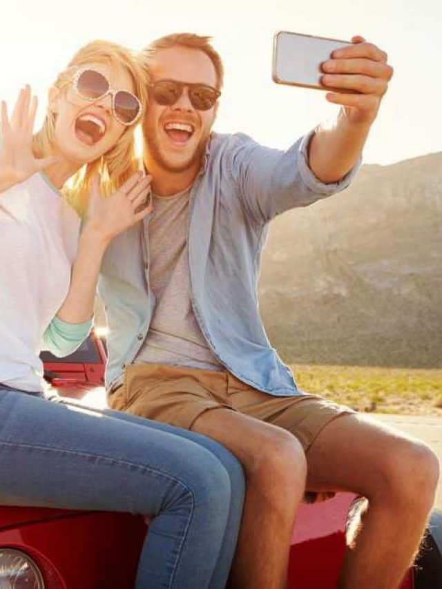 Couple,On,Road,Trip,Sit,On,Convertible,Car,Taking,Selfie