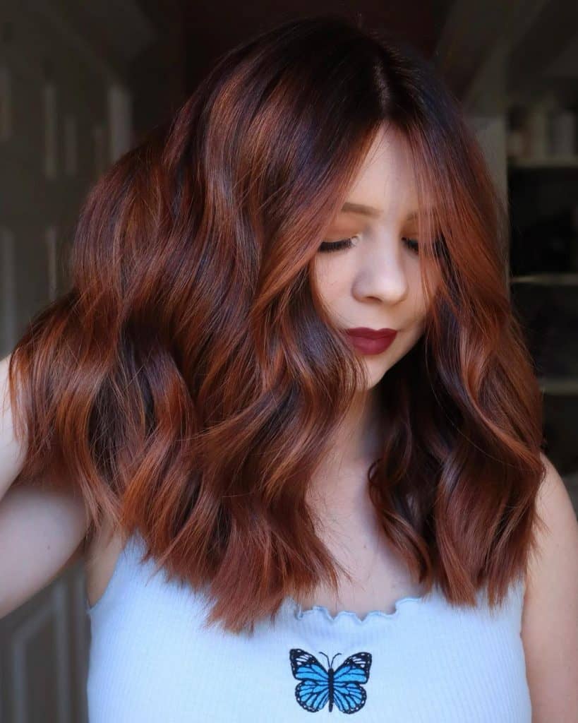 A woman with long, wavy hair wearing a shirt with a butterfly design.