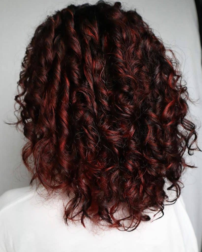 A woman with vibrant red curly hair is depicted in the image.