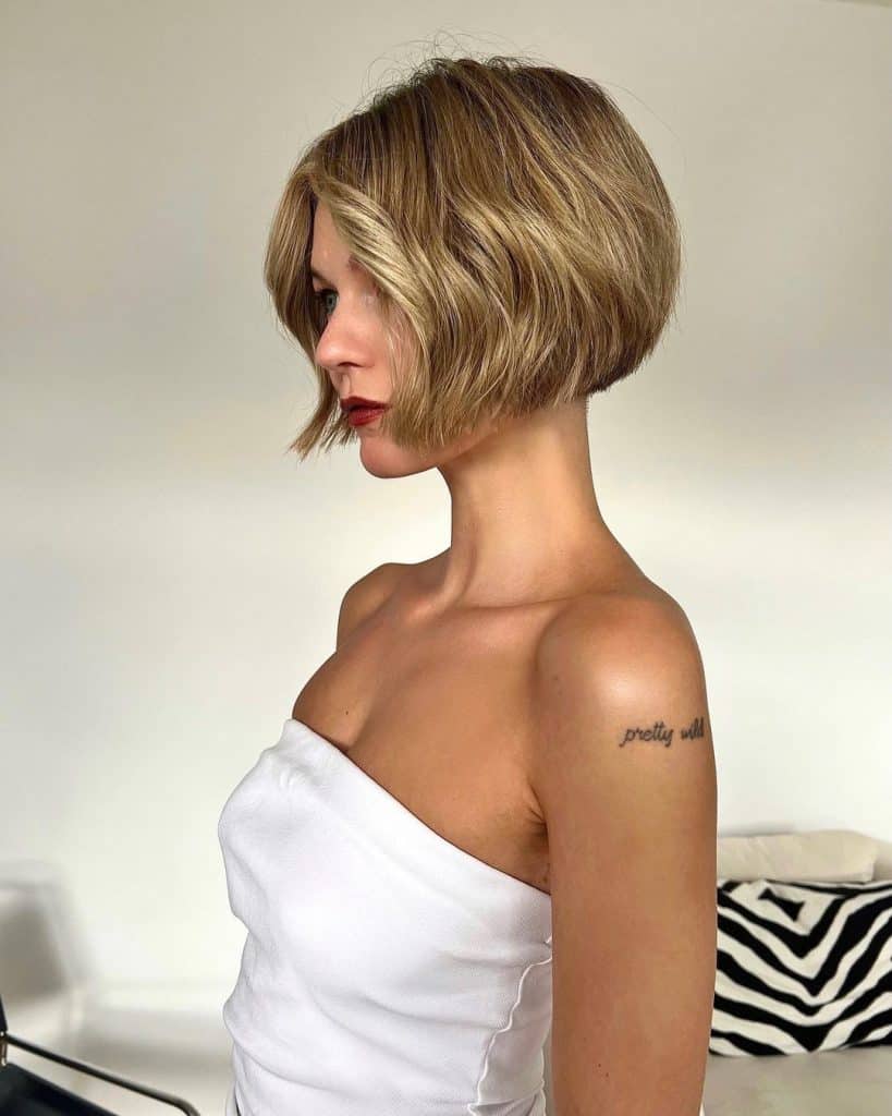 A woman with short blonde hair and a tattoo.