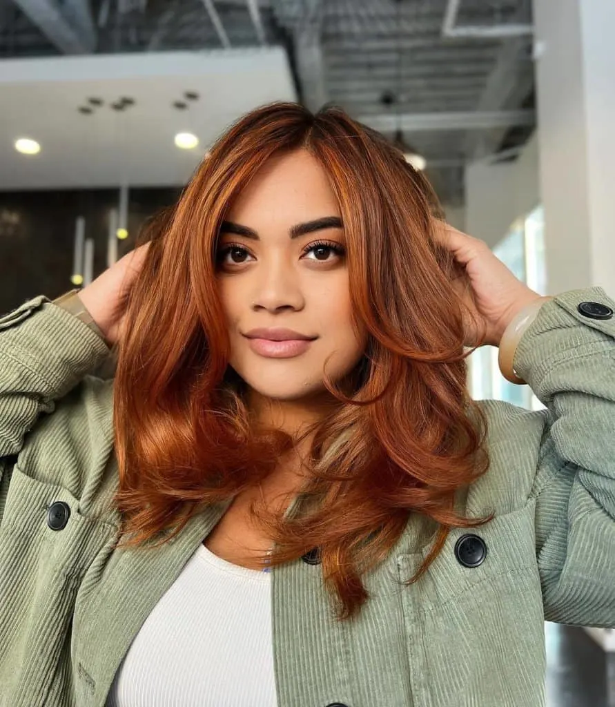 A woman with long red hair getting her hair styled at a salon.