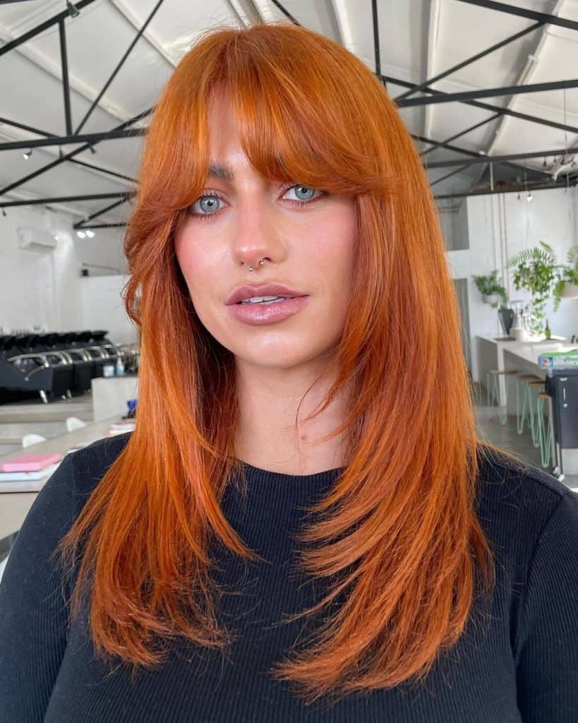 A woman with long red hair and bangs.