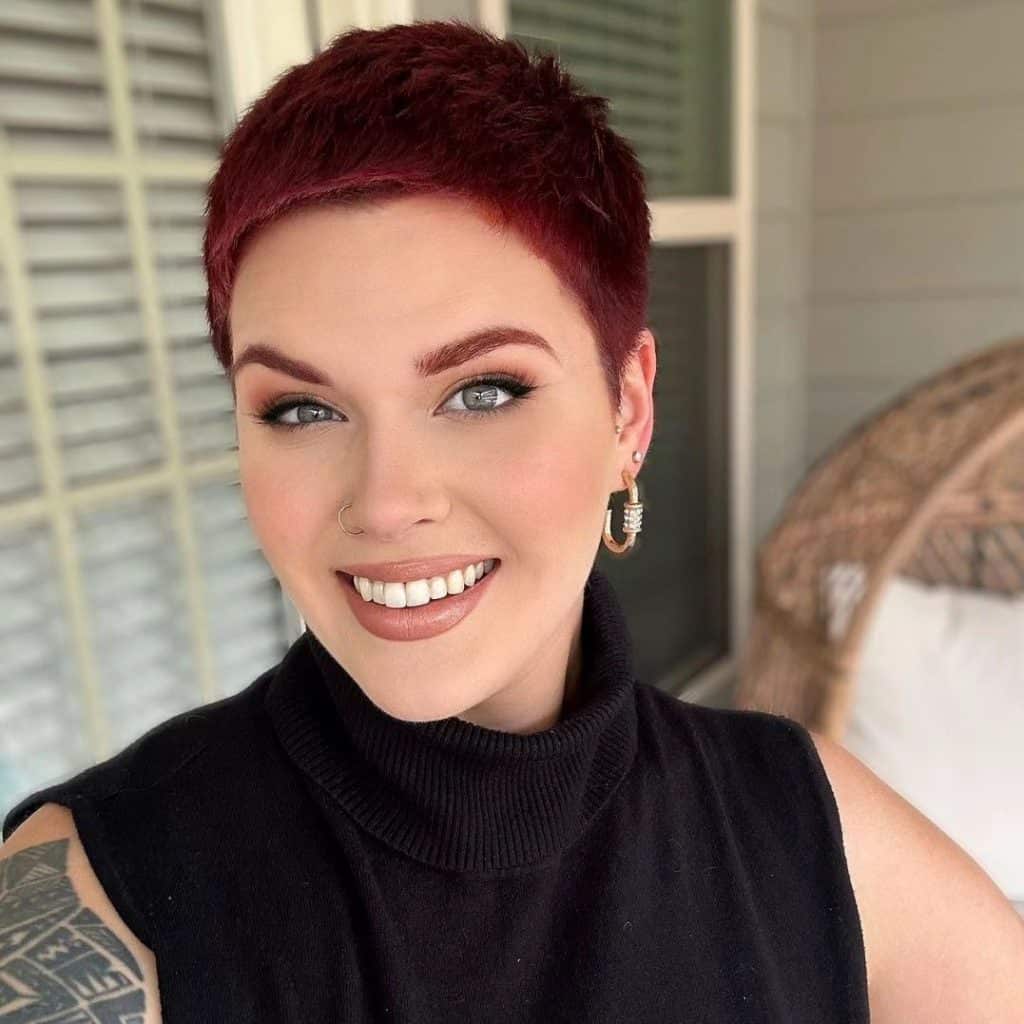 A smiling woman with red hair and tattoos.