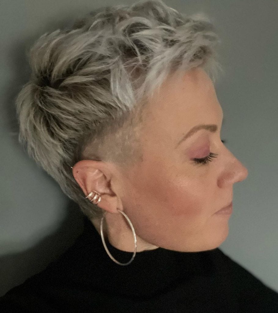 A woman with short hair and earrings, radiating confidence and style.