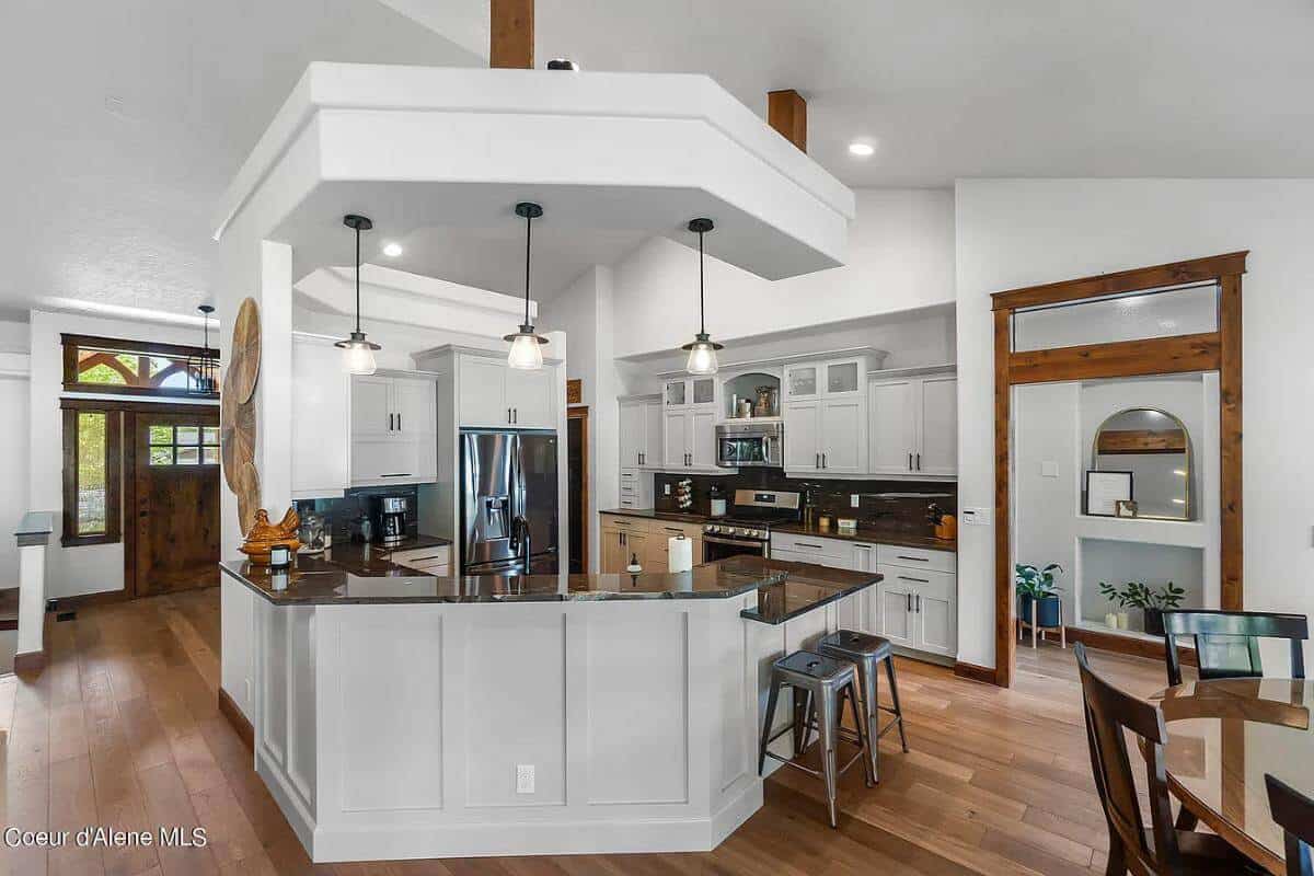 Kitchen with white cabinetry and a peninsula bar illuminated by wrought iron pendants.