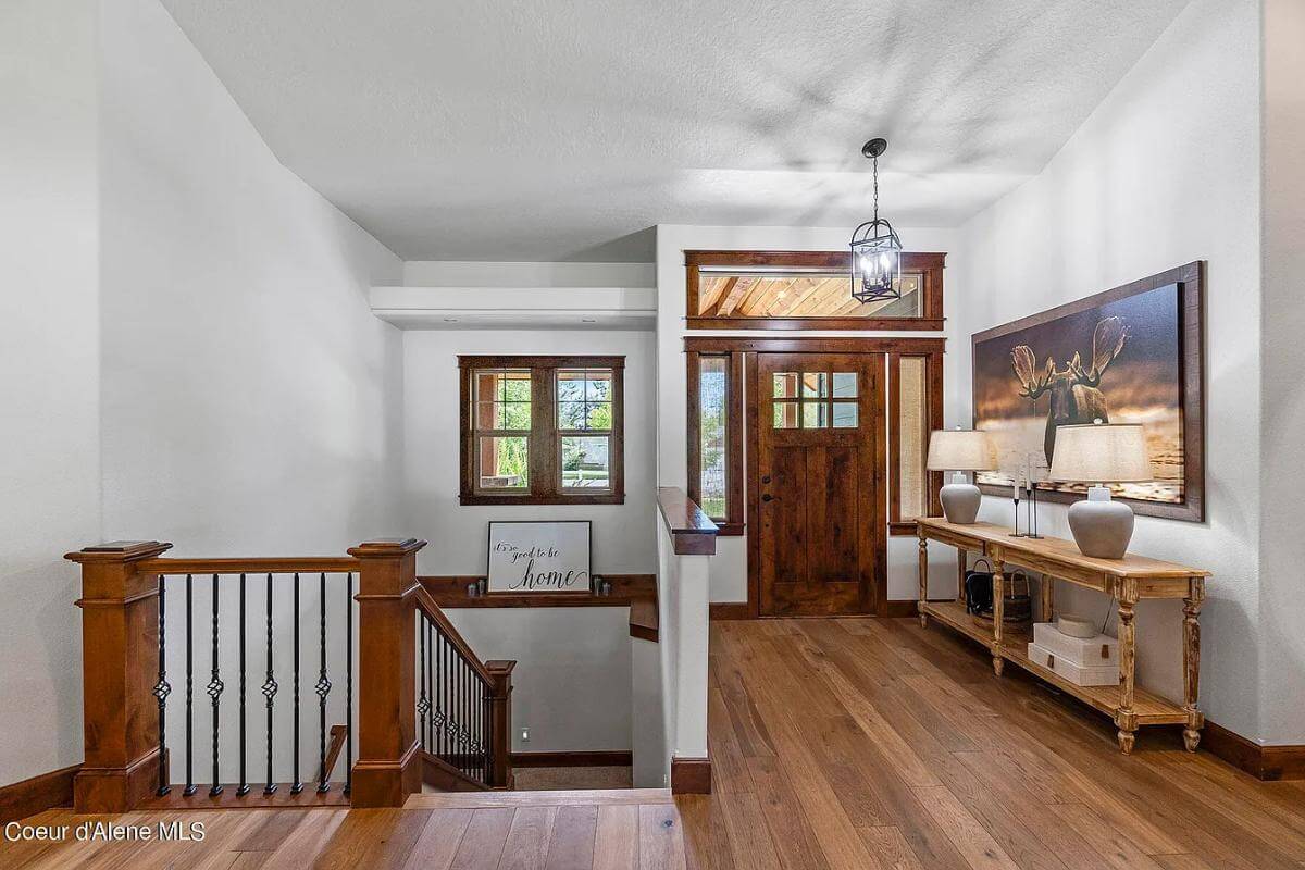 Foyer with a glazed front door, a wooden console table, and a staircase leading down to the basement.