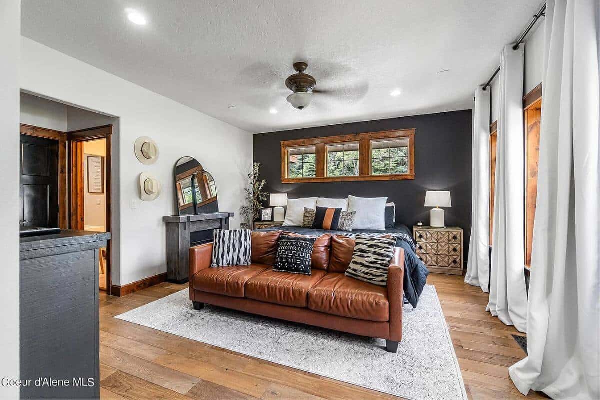 Primary bedroom with a fireplace and a leather sectional situated at the end of the bed.