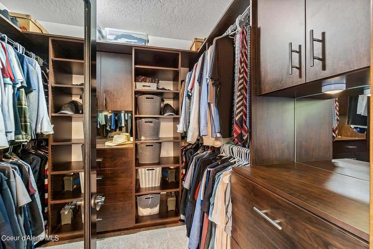 Primary walk-in closet with ample storage and a carpeted floor.