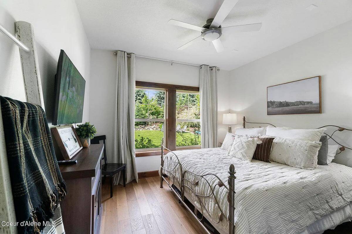 Bedroom with an ornate metal bed and wooden framed windows.