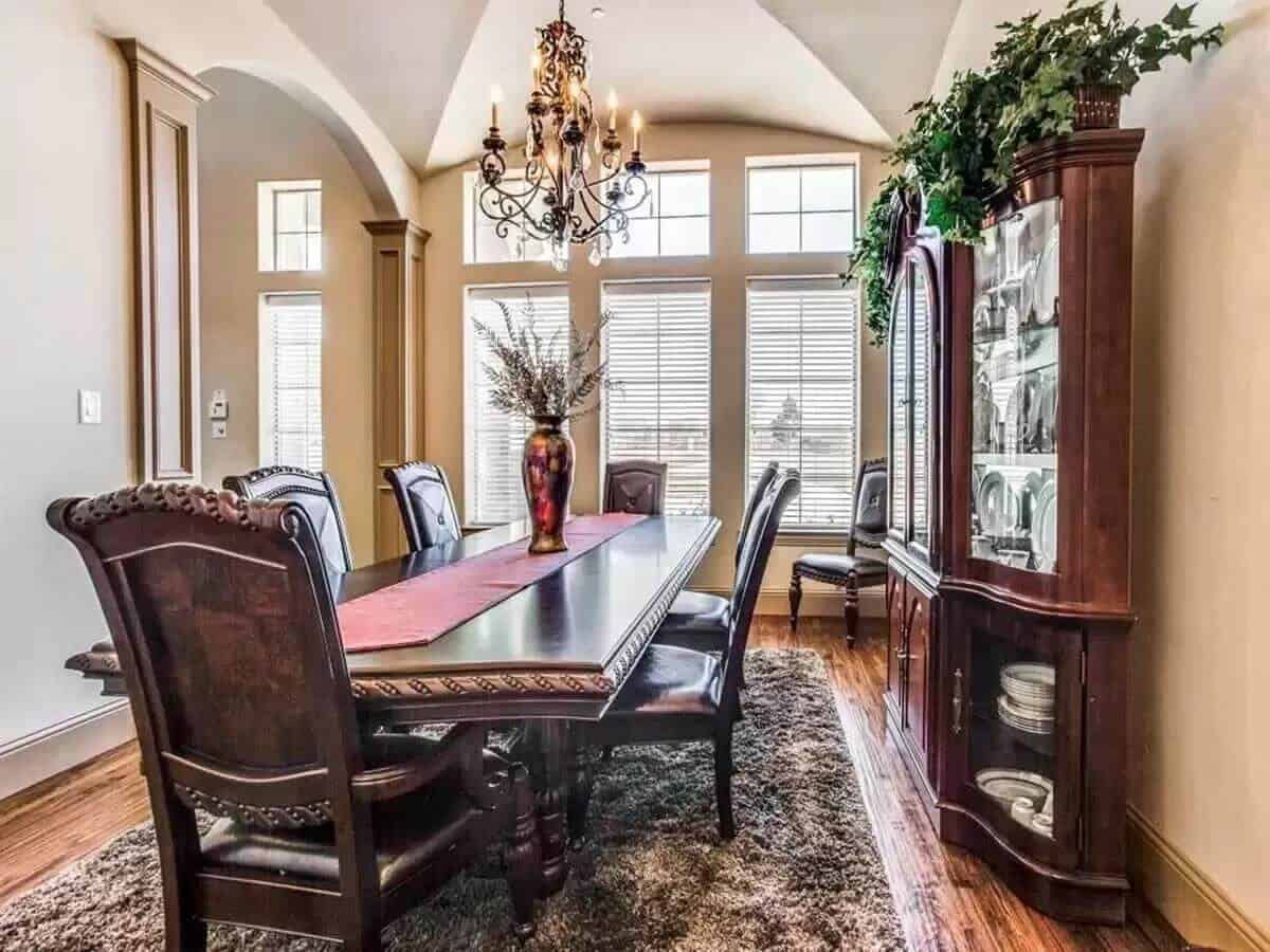 Dining room with a china cabinet and a dark wood dining set illuminated by an ornate chandelier.