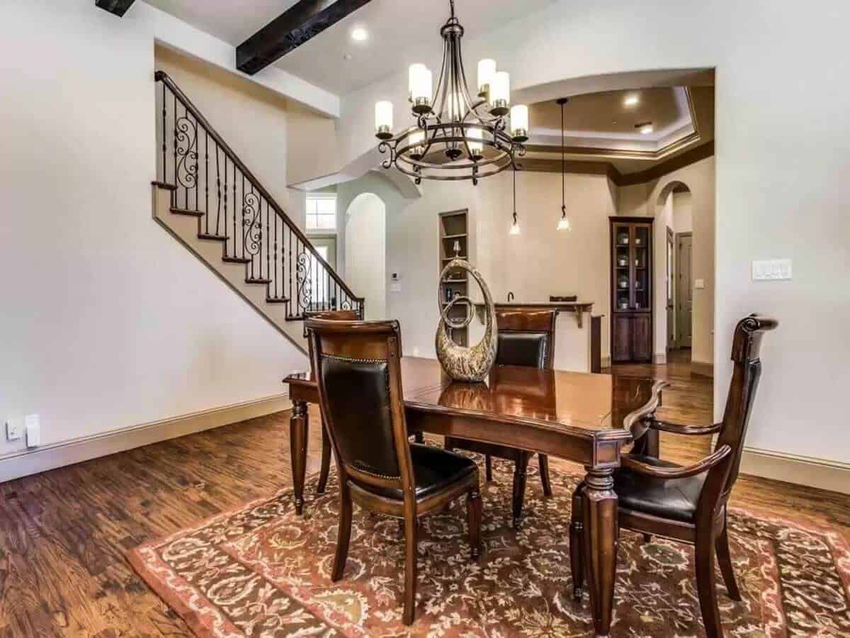 Breakfast nook with a wrought iron chandelier and a wooden dining set over the patterned area rug.