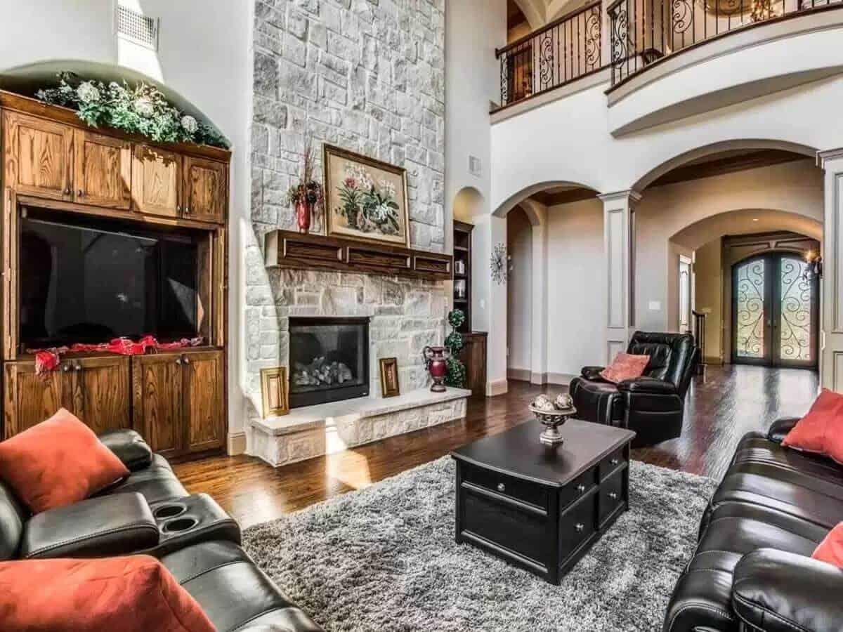 Family room with leather seats, a black coffee table, and a stone fireplace.