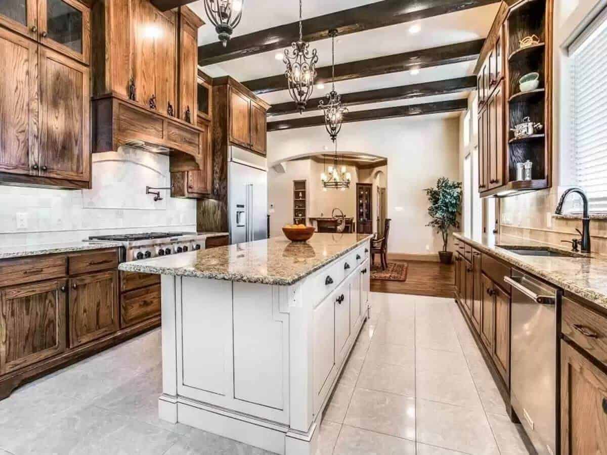 Kitchen with rustic cabinets and a center island under a beamed ceiling.