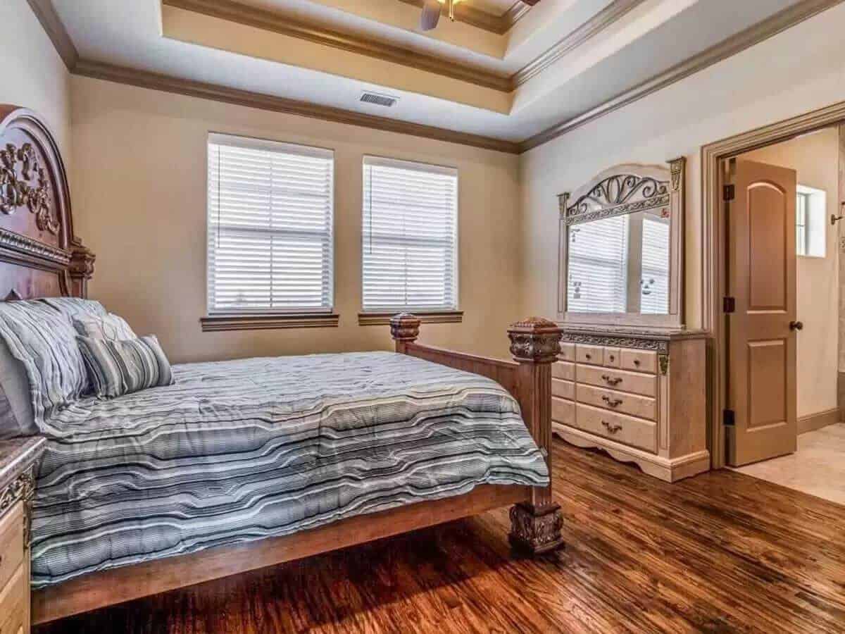 Bedroom with a step ceiling, a wooden bed, and a vanity dresser.