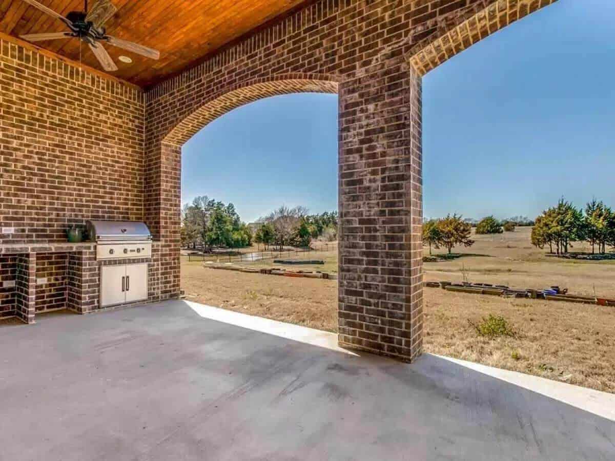 Outdoor lounge with brick walls, archways, and a summer kitchen.