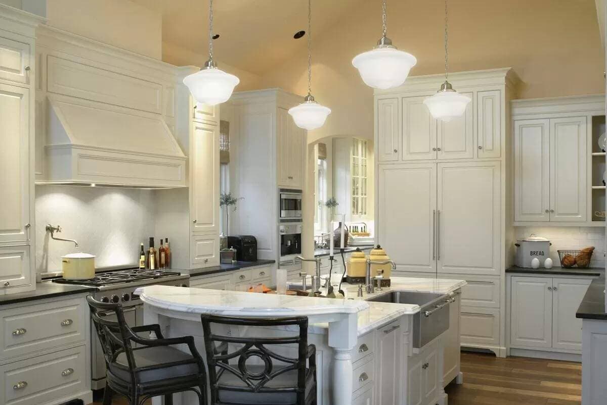 Kitchen with white cabinets and a matching island with seating for two.