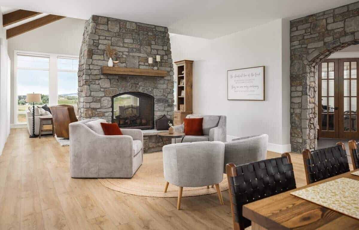 Sitting area with gray chairs and a double sided fireplace shared by the family room.