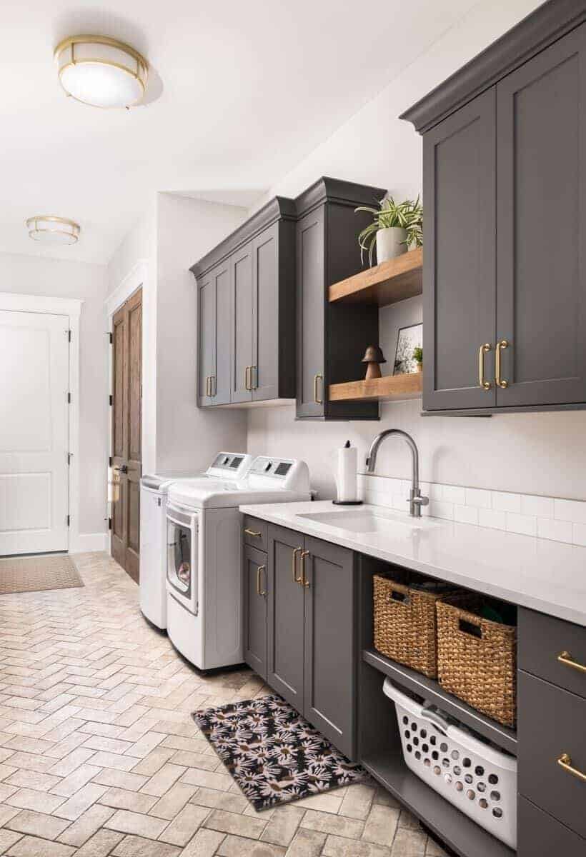 Laundry room with black cabinets, contrasting countertops, and herringbone-tiled flooring.