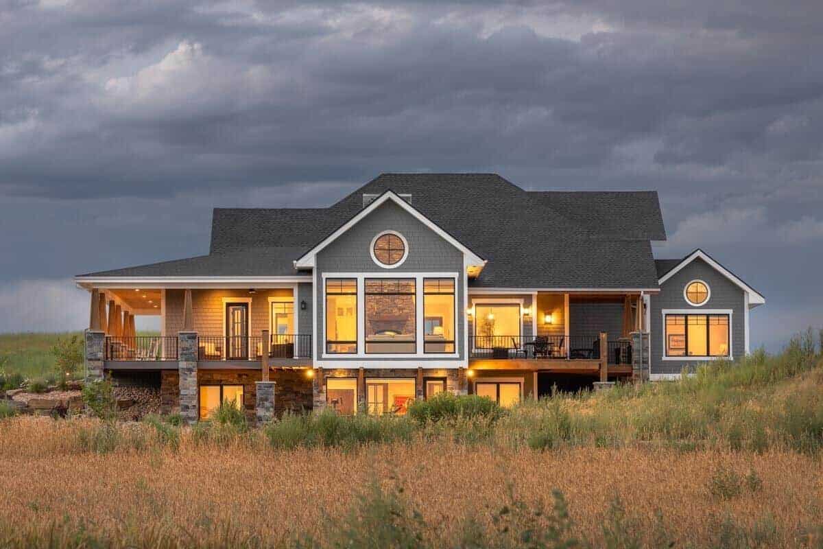 Rear view of the house showcasing the wraparound porch flooded by ambient lighting.