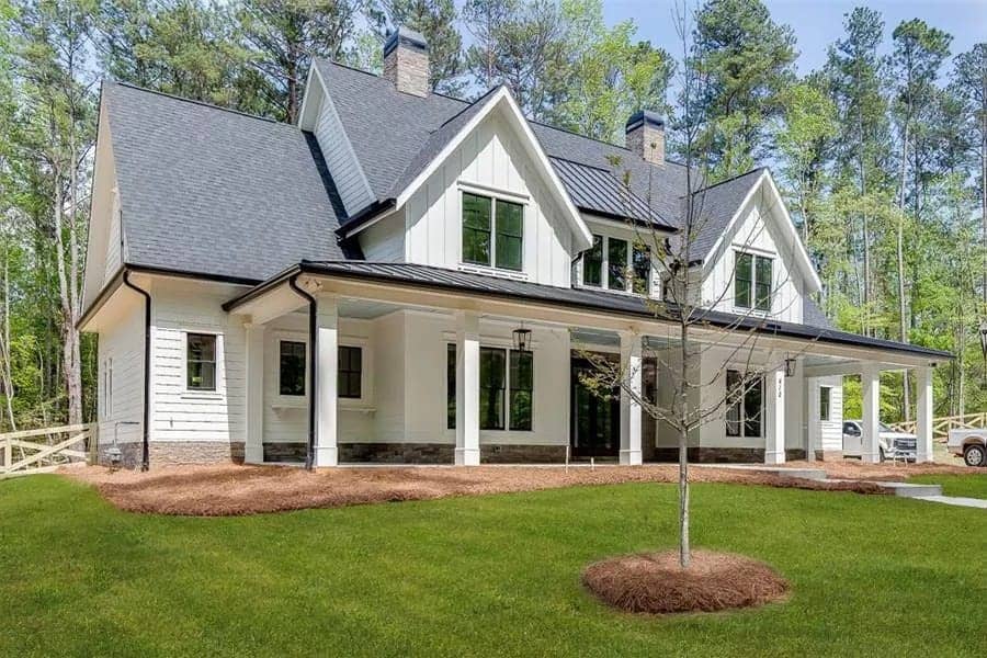 Front view with twin gables, stone chimneys, and an expansive entry porch supported by white columns.