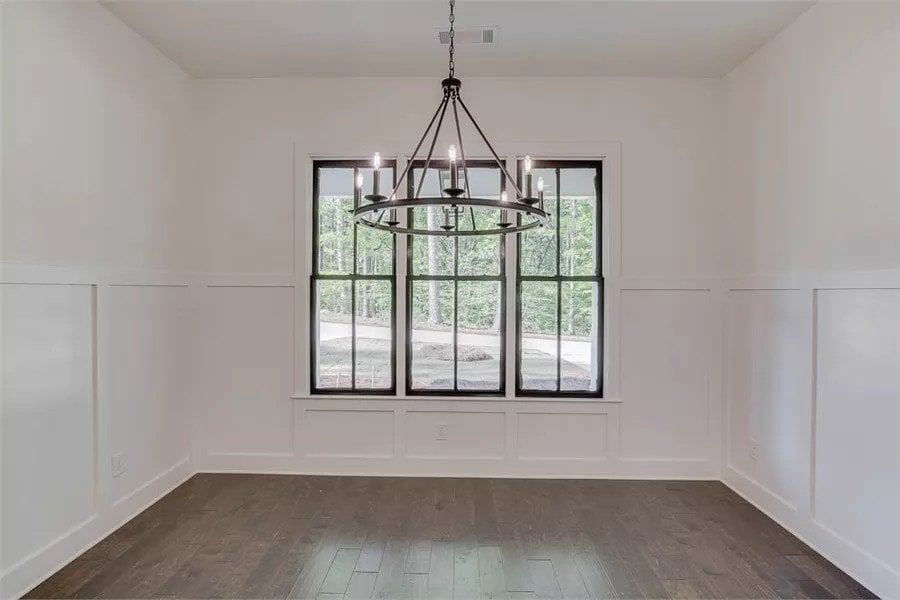 Dining room with wainscoted walls and a round chandelier.