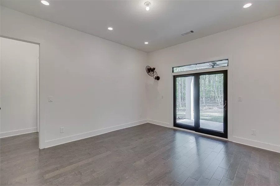 Primary bedroom with hardwood flooring and sliding glass doors that open to the rear porch.