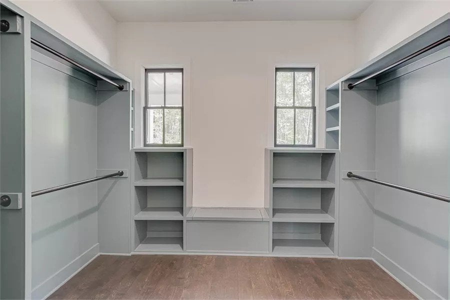 Primary walk-in closet with built-in shelves and hardwood flooring.