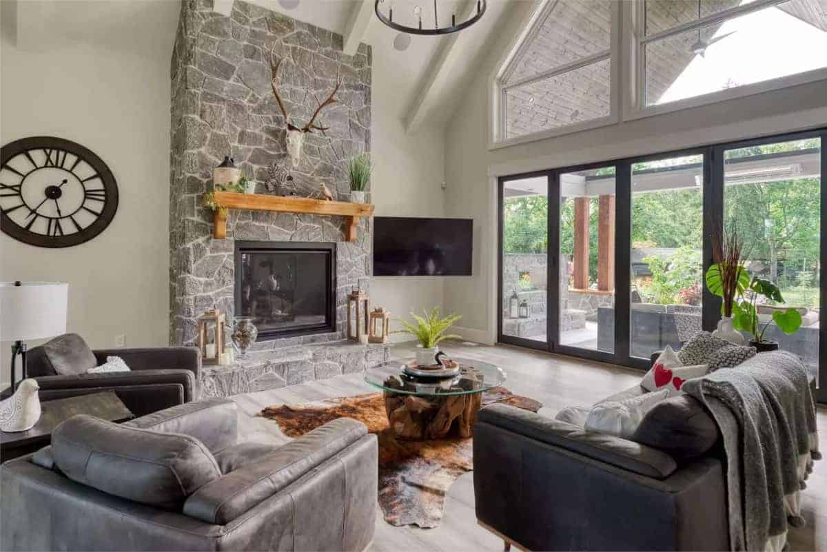 Great room with leather sofas, a stone fireplace, and a wall-mounted TV.