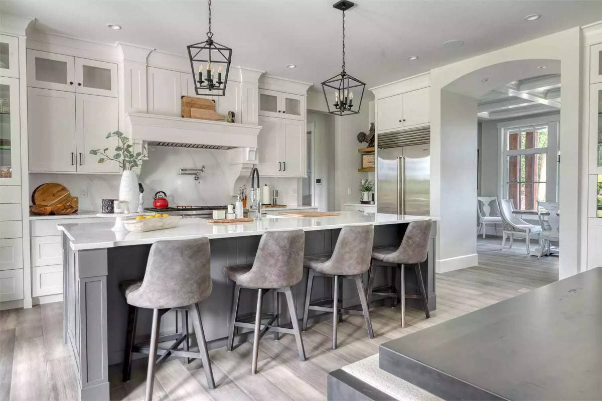 Kitchen with white cabinets and a breakfast island with seating for four.