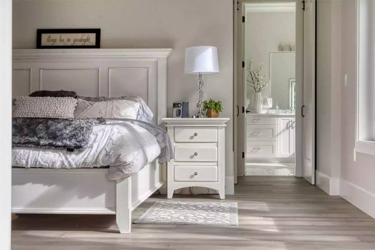 Primary bedroom with white furnishings and an ensuite bathroom.