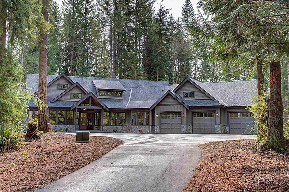 A charming Craftsman-style home with an abundance of glass windows and dark gray roof that goes quite well with the surrounding tall trees.