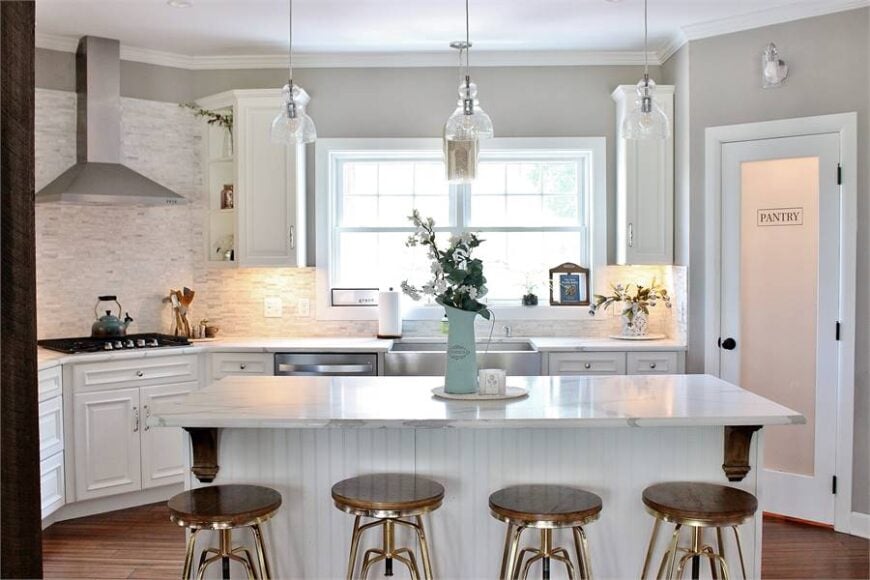 Glass dome pendants illuminate the white beadboard island that's paired with round bar stools.