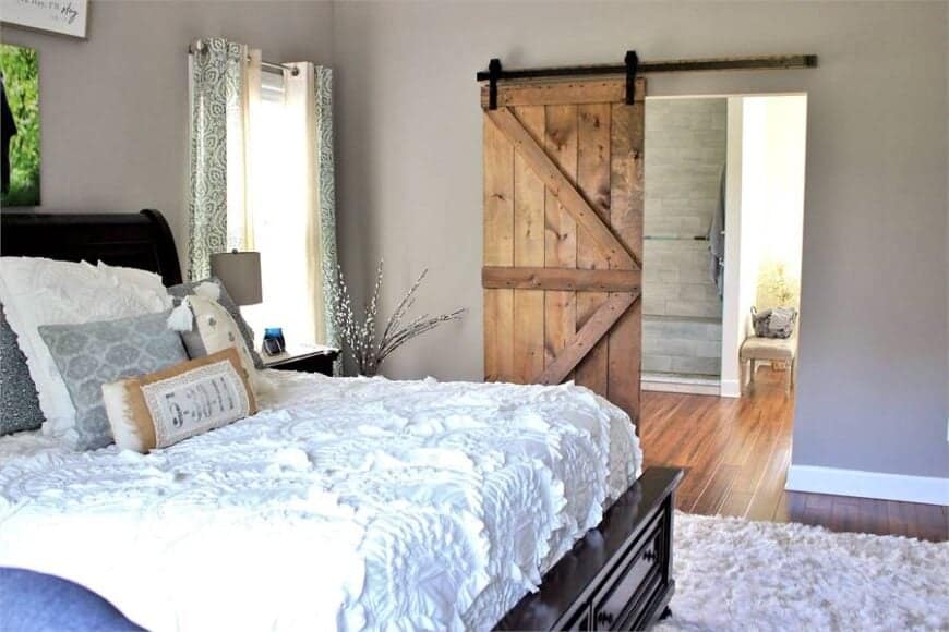 Primary bedroom with wide-plank flooring and a barn door that leads to the primary bath.