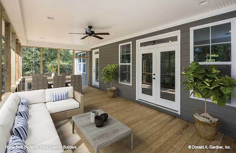 Spacious screened porch with outdoor dining and living. Green potted plants create a fresh ambiance to the area.