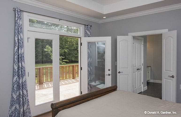 Primary bedroom with a dark wood bed and a french door that opens to the sun deck.