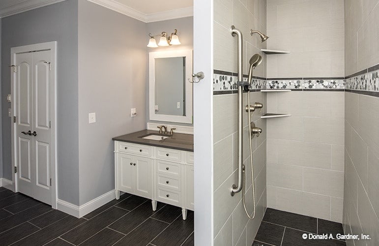 The primary bathroom offers a sink vanity and a shower area mounted with corner shelves and chrome fixtures.